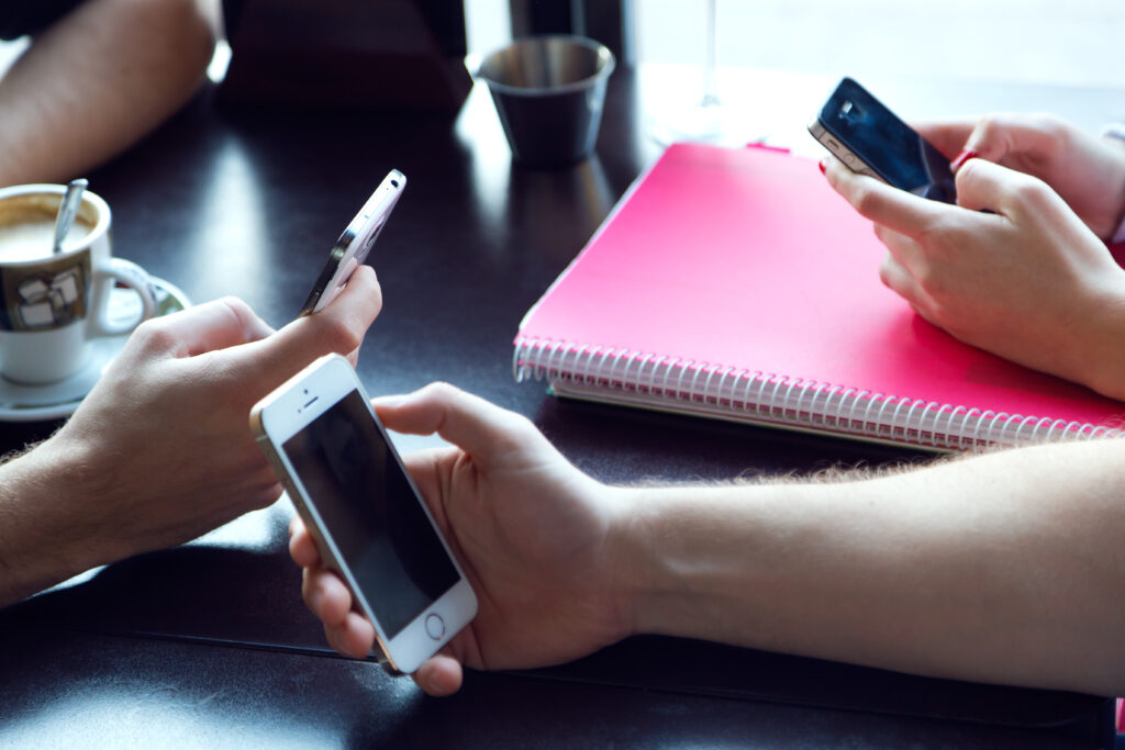 Apple Stops Signing iOS 18.4.1: No More Downgrades Allowed 2 group friends using mobile phone cafe