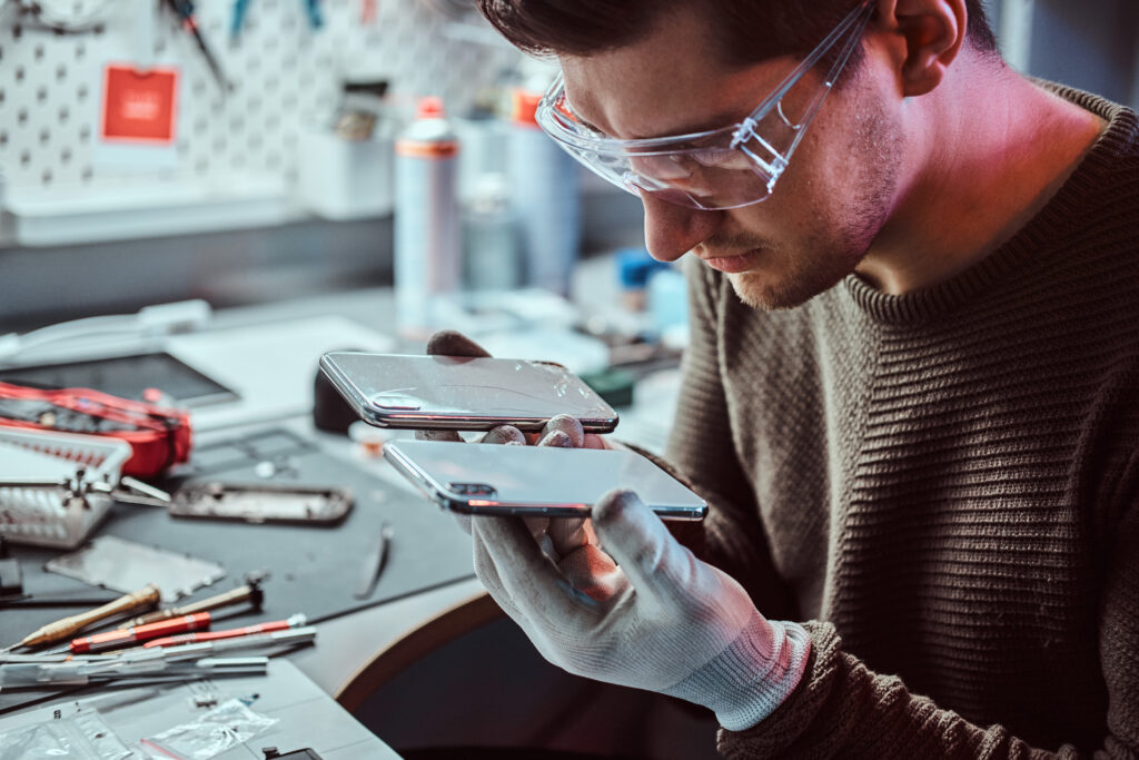 electronic technician holds two identical smartphones comparison one hand broken another new