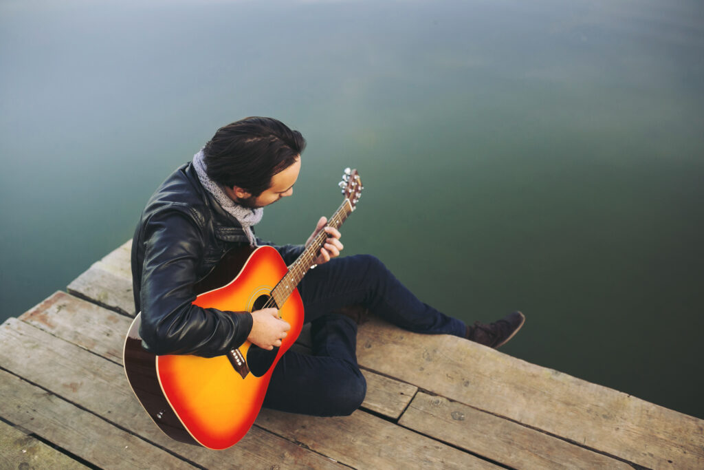 young man playing guitar lake